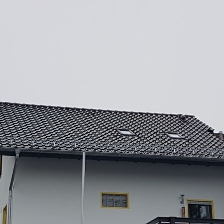 Neu eingedecktes schwarzes Dach auf Haus mit weißer Fassade