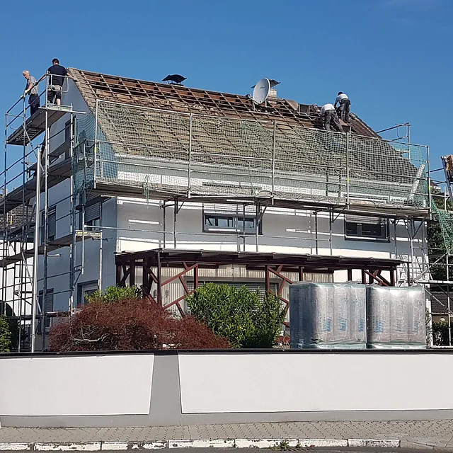 Haus mit abgedecktem Dach und aufgebautem Gerüst für Dacharbeiten