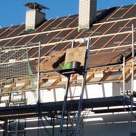 Dachdeckerarbeiten und Umdeckung eines Hauses mit aufgebautem Gerüst und Arbeitsmaterialien